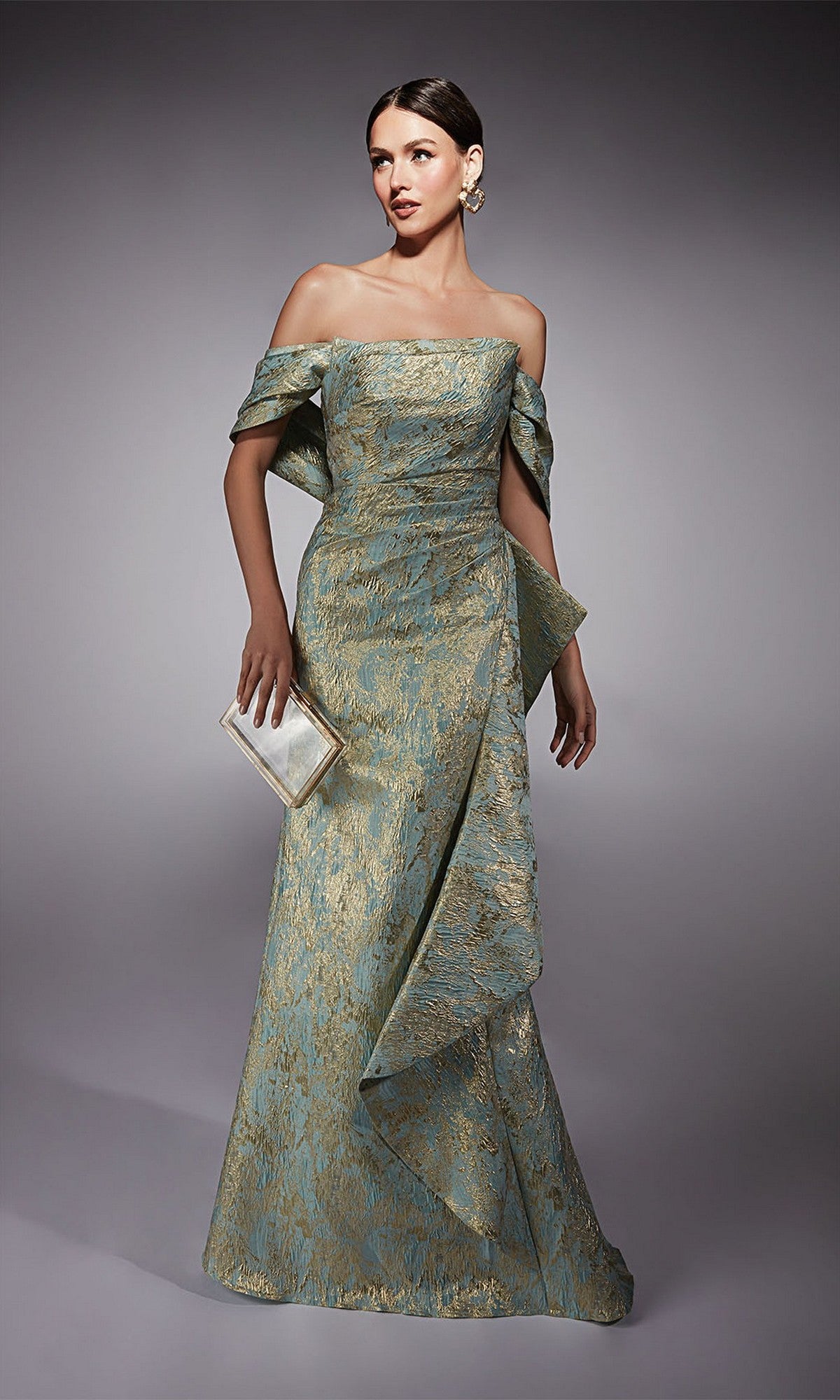 A woman stands against a plain gray background wearing the Alyce 27750 long formal dress in sea glass/gold, featuring an off-the-shoulder metallic jacquard brocade design with a mermaid skirt and holding a rectangular clutch purse.